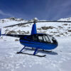 Hélicoptère Robinson R44 devant les Alpes valaisannes enneigées près de Sion